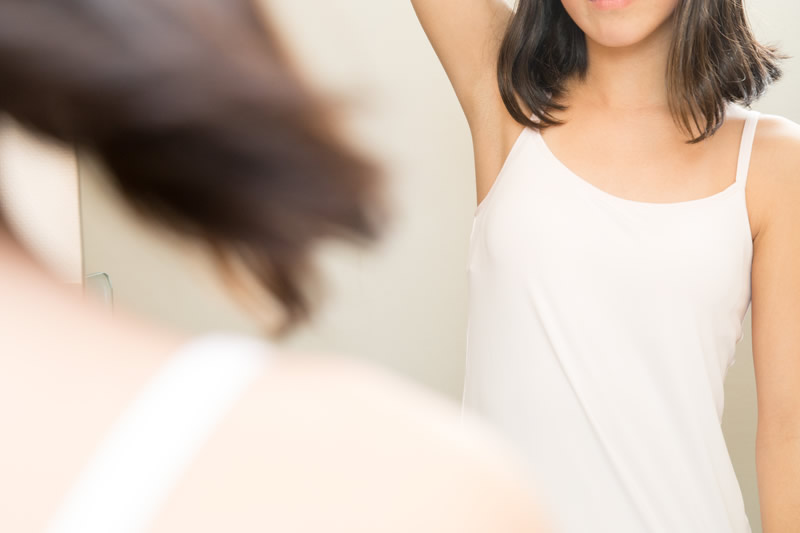 鏡で脇を見る腋臭の女性